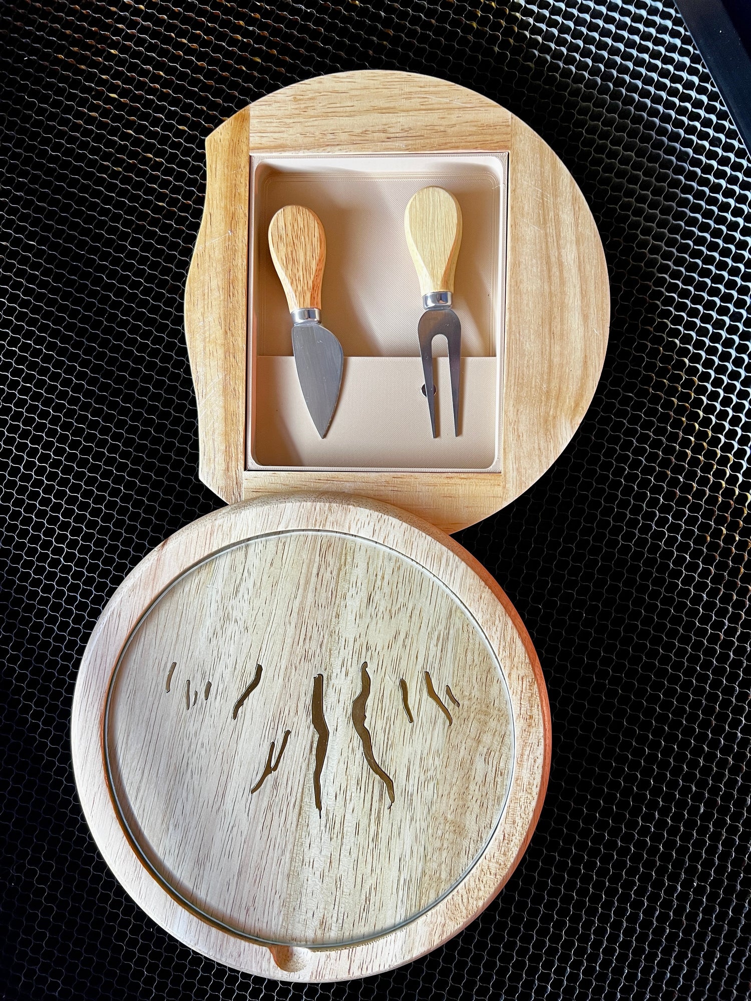 Custom round wooden serving board with brass Finger Lakes inserts, glass top, and magnetic utensil tray by Finger Lakes Laser.