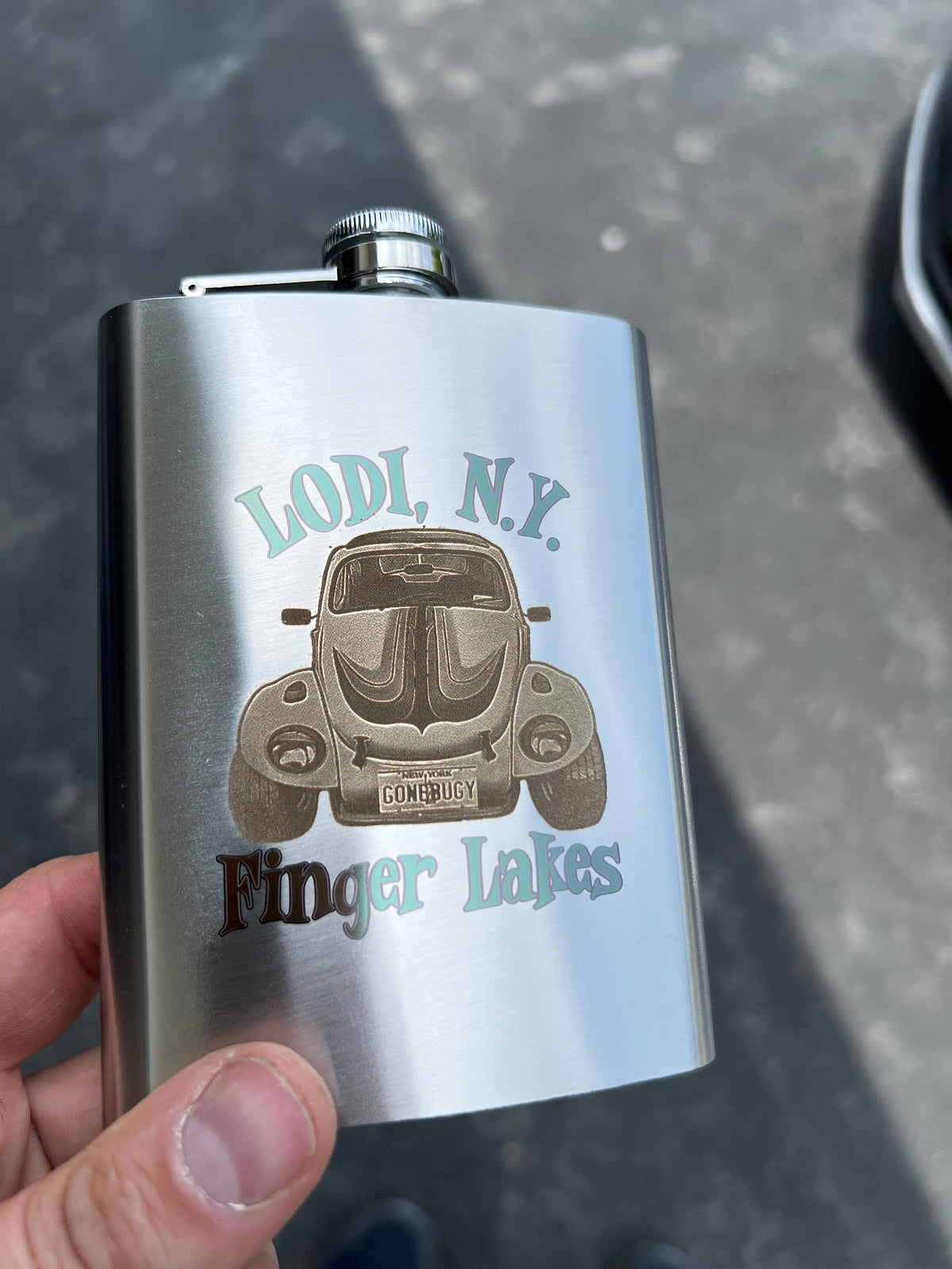 Custom stainless steel flasks engraved with a local business design, vehicle artwork, and color laser marking by Finger Lakes Laser.